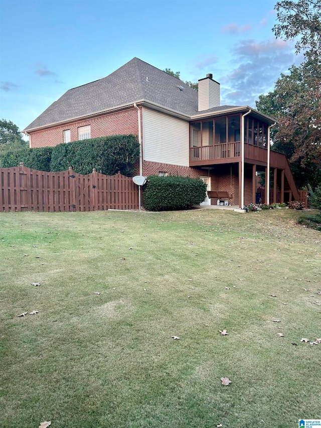 view of side of home featuring a wooden deck, a sunroom, and a yard