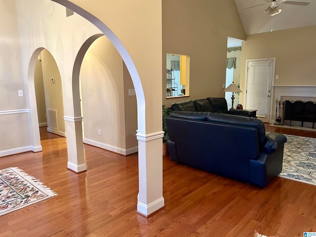 living room featuring high vaulted ceiling, decorative columns, hardwood / wood-style flooring, and ceiling fan