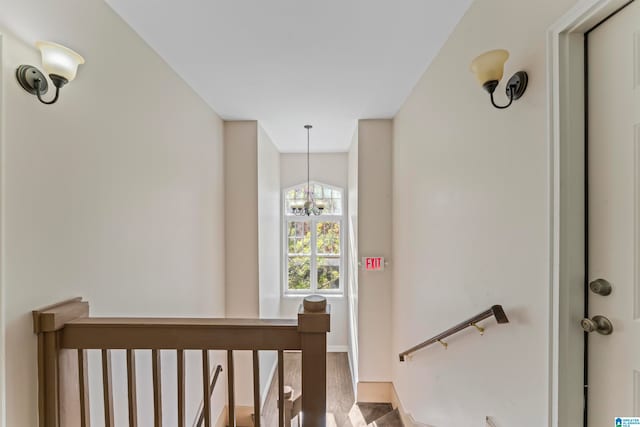 stairway featuring wood-type flooring and a notable chandelier