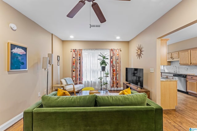 living room with ceiling fan, light hardwood / wood-style flooring, and sink