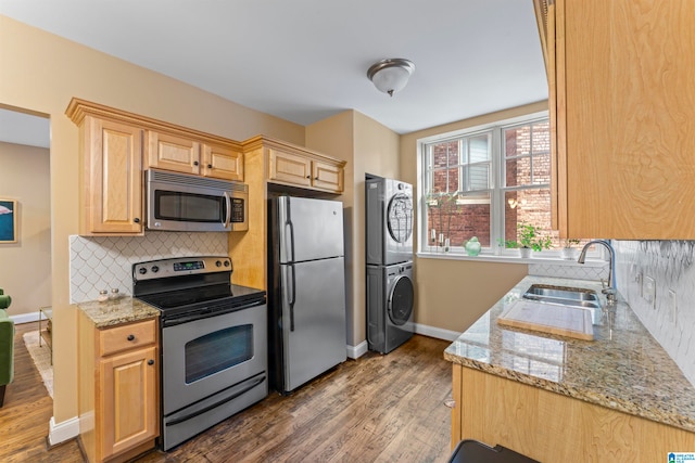 kitchen featuring sink, dark hardwood / wood-style floors, backsplash, stacked washer / dryer, and appliances with stainless steel finishes