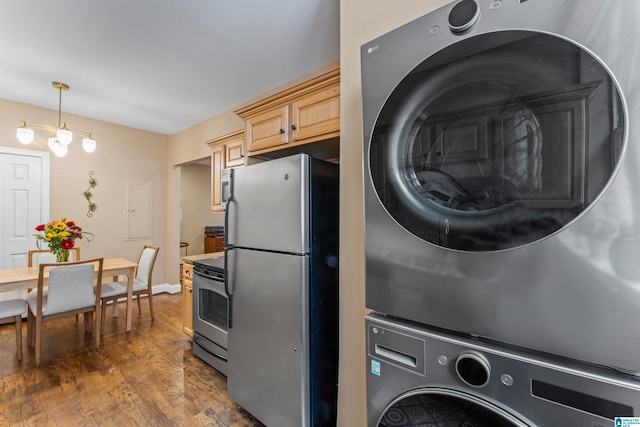 clothes washing area featuring dark hardwood / wood-style floors, stacked washer / dryer, and an inviting chandelier