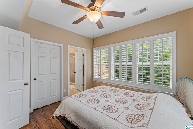 bedroom featuring multiple windows, ceiling fan, dark hardwood / wood-style flooring, and ensuite bathroom