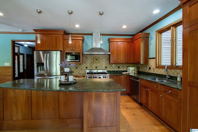 kitchen with sink, hanging light fixtures, wall chimney exhaust hood, a kitchen island, and stainless steel appliances