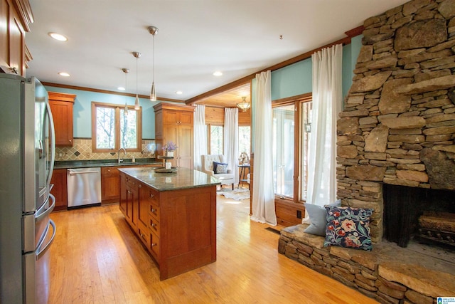 kitchen featuring hanging light fixtures, light hardwood / wood-style flooring, backsplash, a kitchen island, and appliances with stainless steel finishes