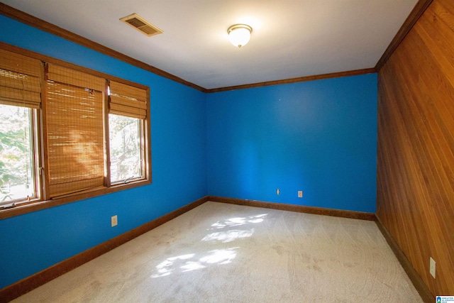 carpeted empty room featuring crown molding and wooden walls