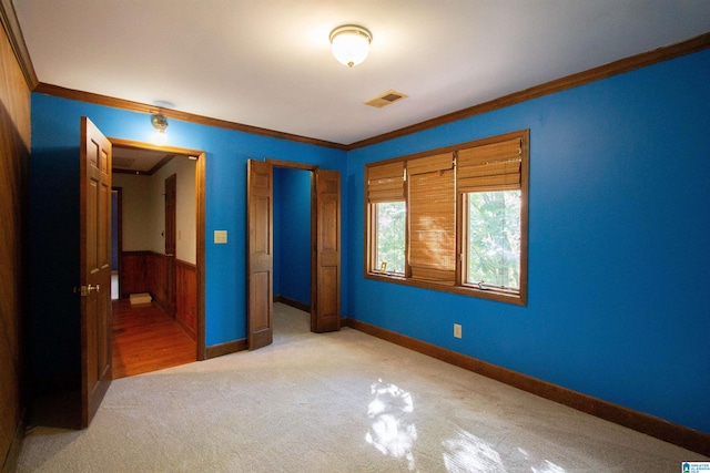 unfurnished bedroom with wood walls, a closet, light colored carpet, and ornamental molding