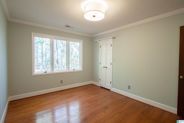 spare room with crown molding and light wood-type flooring