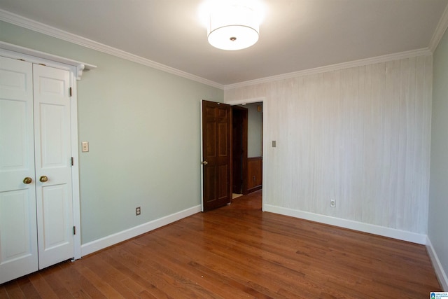 unfurnished bedroom featuring hardwood / wood-style flooring, crown molding, and a closet