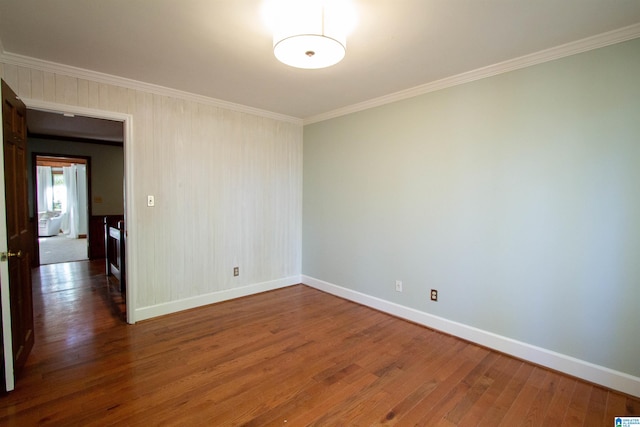 empty room with dark hardwood / wood-style floors and crown molding