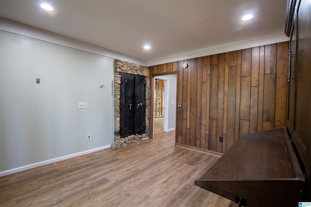 spare room featuring wood walls and light hardwood / wood-style flooring