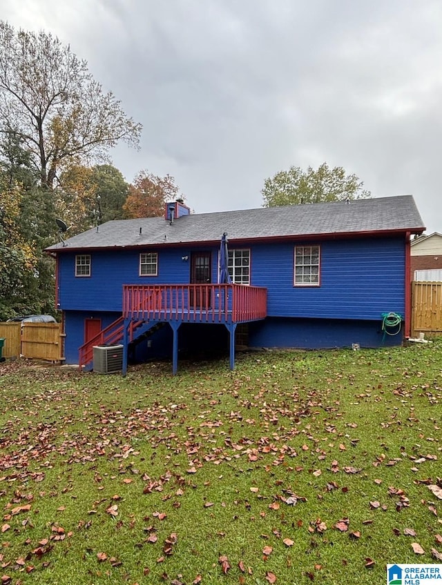 rear view of property with a deck, central air condition unit, and a lawn