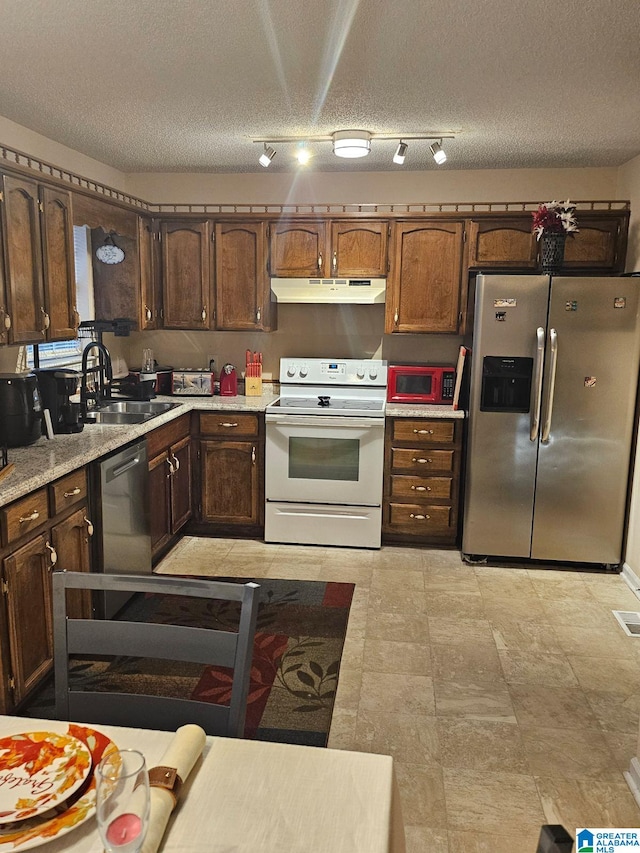 kitchen with dark brown cabinets, appliances with stainless steel finishes, a textured ceiling, and sink