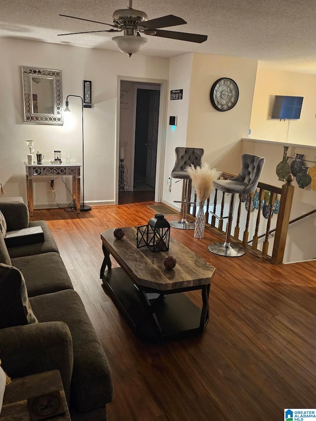 living room featuring hardwood / wood-style flooring, ceiling fan, and a textured ceiling