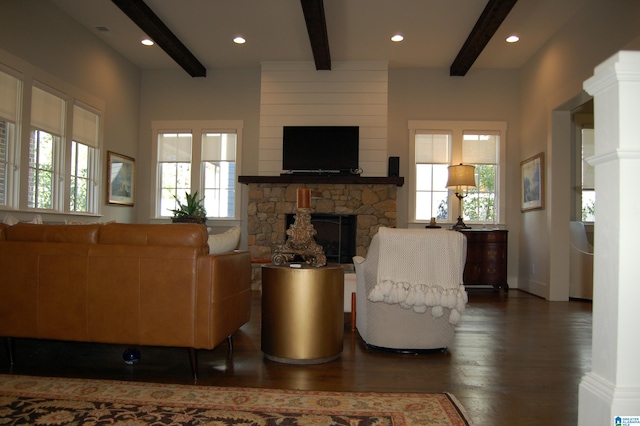 living room featuring a healthy amount of sunlight, a fireplace, beamed ceiling, and dark hardwood / wood-style floors