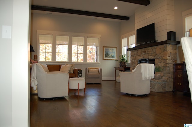 living room with dark wood-type flooring, a fireplace, a healthy amount of sunlight, and beam ceiling