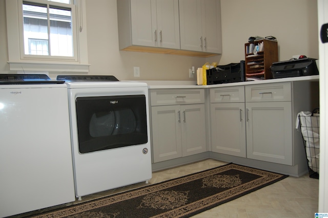 washroom with light parquet flooring, washing machine and dryer, and cabinets