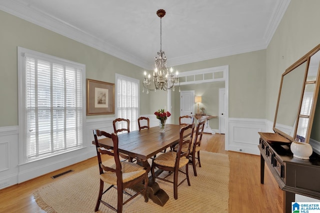 dining space featuring a notable chandelier, crown molding, and light hardwood / wood-style flooring