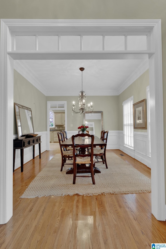 dining space featuring light wood-type flooring, a chandelier, and ornamental molding