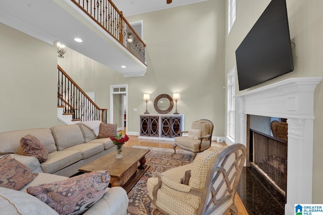 living room with a high ceiling, wood-type flooring, and crown molding