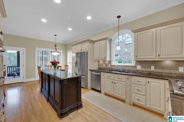 kitchen featuring backsplash, appliances with stainless steel finishes, decorative light fixtures, sink, and light hardwood / wood-style flooring