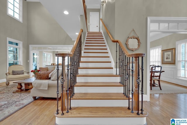 stairs with a wealth of natural light, hardwood / wood-style flooring, and a towering ceiling