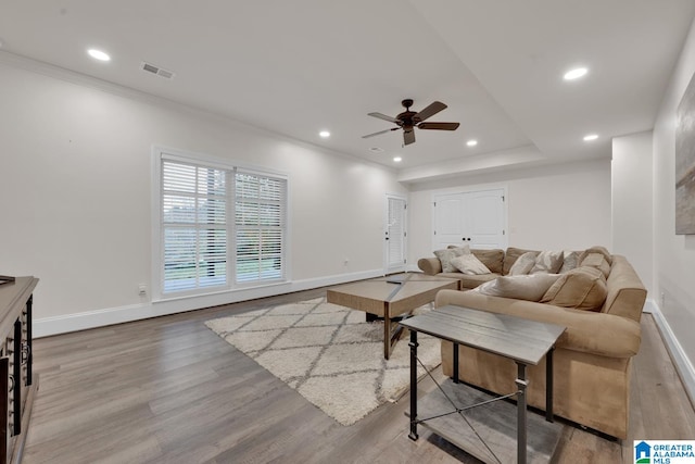 living room featuring hardwood / wood-style floors, ceiling fan, and crown molding