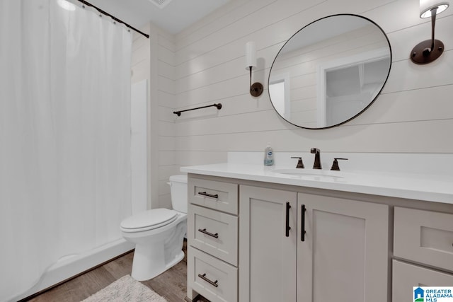 bathroom featuring toilet, hardwood / wood-style floors, wood walls, vanity, and a shower with shower curtain