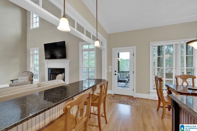 kitchen with pendant lighting, light hardwood / wood-style flooring, ornamental molding, and a healthy amount of sunlight