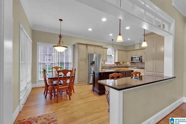 kitchen featuring stainless steel appliances, hanging light fixtures, light hardwood / wood-style flooring, crown molding, and a kitchen island