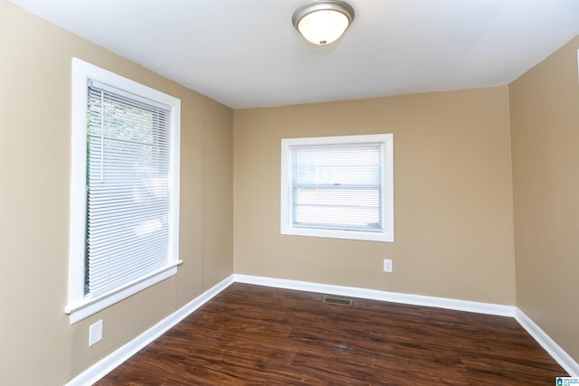 empty room featuring dark hardwood / wood-style flooring and a healthy amount of sunlight