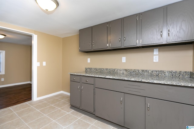 kitchen with gray cabinets, light stone counters, and light tile patterned floors