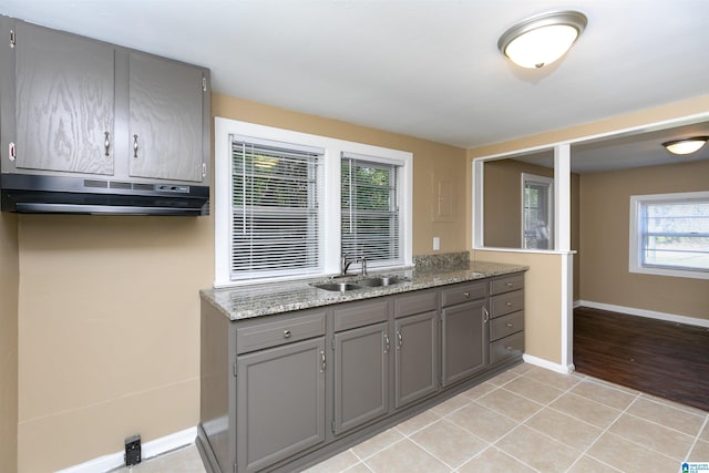 kitchen featuring ventilation hood, sink, light stone countertops, and light wood-type flooring