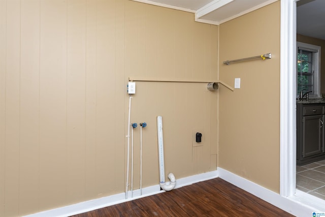 laundry room with dark wood-type flooring, wooden walls, sink, and electric dryer hookup