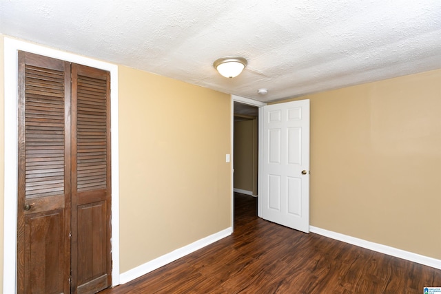 unfurnished bedroom with a textured ceiling, a closet, and dark hardwood / wood-style flooring