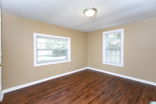 spare room featuring dark wood-type flooring and a healthy amount of sunlight