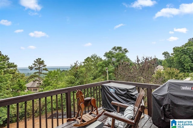 wooden terrace featuring area for grilling and a water view