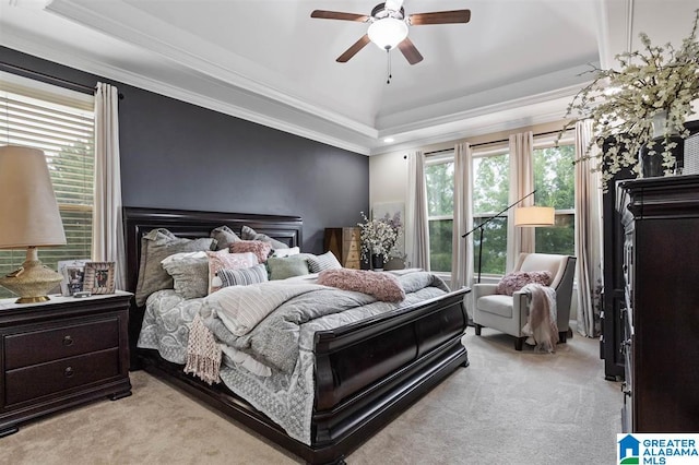 carpeted bedroom with ornamental molding, ceiling fan, and a tray ceiling