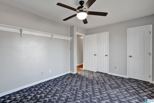 unfurnished bedroom with ceiling fan and dark colored carpet