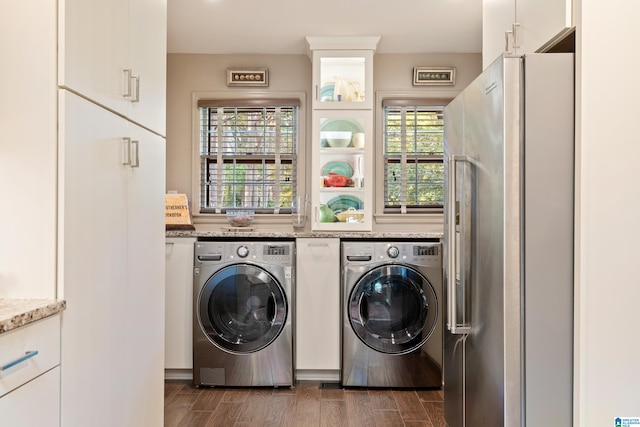 clothes washing area with dark wood-type flooring, washing machine and clothes dryer, and plenty of natural light