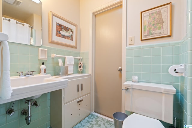 bathroom with toilet and tile walls