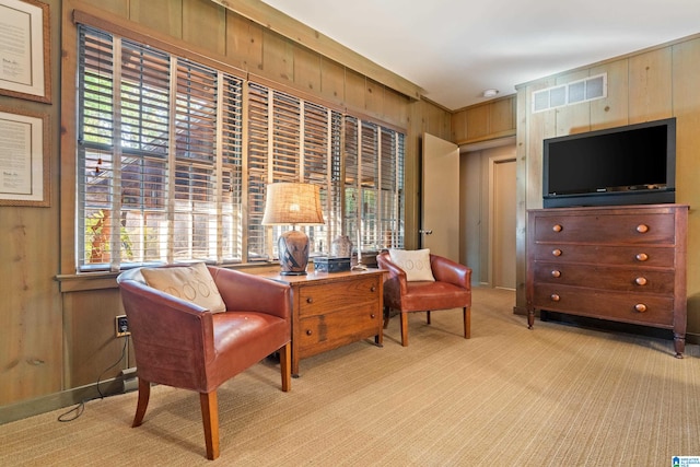 sitting room with wooden walls and light colored carpet