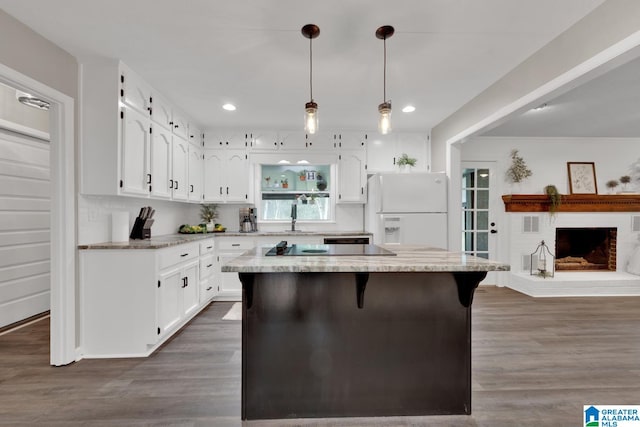 kitchen with white cabinets, hanging light fixtures, white refrigerator with ice dispenser, dark hardwood / wood-style floors, and a kitchen island