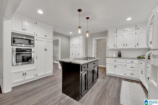 kitchen with light stone counters, a kitchen island, appliances with stainless steel finishes, pendant lighting, and light hardwood / wood-style floors