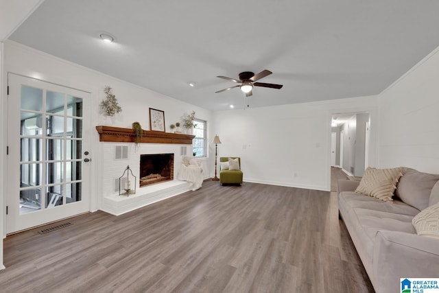 unfurnished living room featuring a brick fireplace, ornamental molding, hardwood / wood-style flooring, and ceiling fan