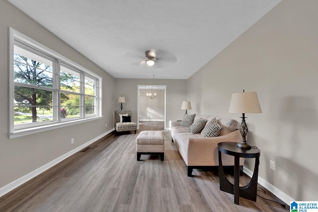 living room featuring wood-type flooring and ceiling fan with notable chandelier