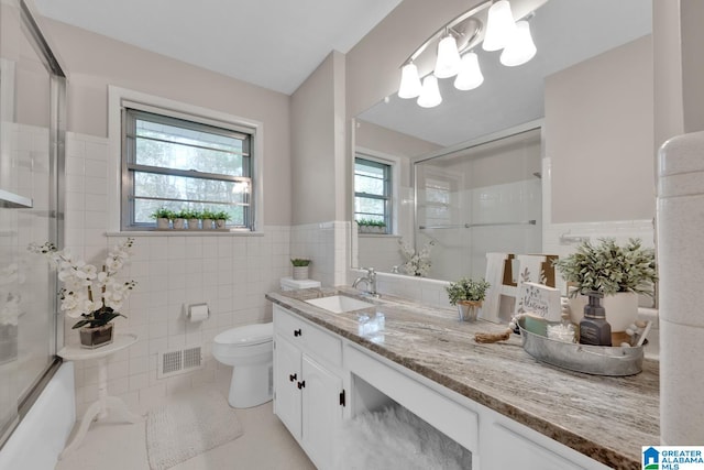 bathroom with vanity, plenty of natural light, an enclosed shower, and tile walls