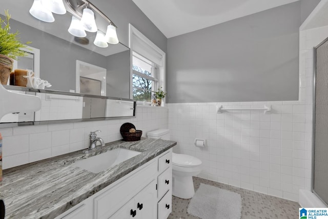 bathroom featuring tile walls, a shower with door, vanity, tile patterned flooring, and toilet