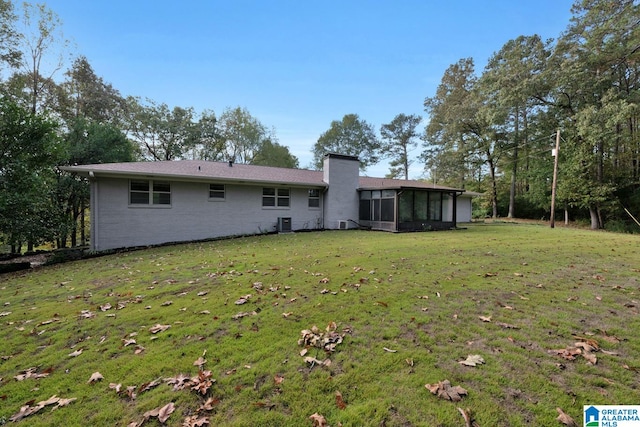 back of property with a lawn and a sunroom