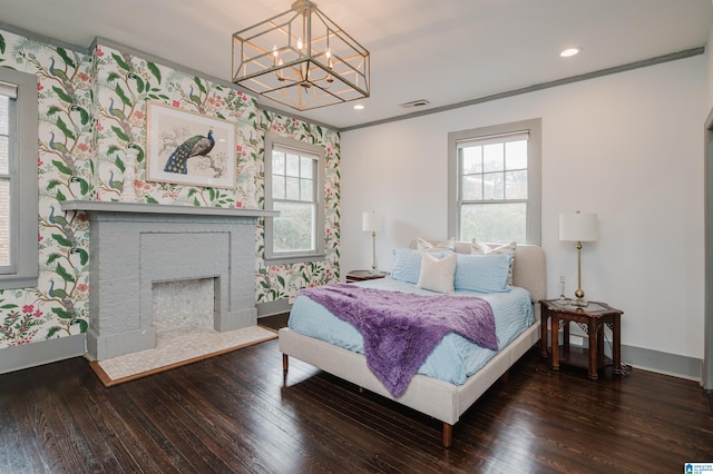 bedroom with a brick fireplace, dark hardwood / wood-style flooring, multiple windows, and crown molding